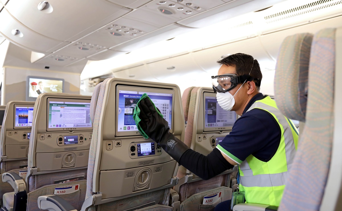 A member of cleaning staff wearing protective mask disinfects a seat